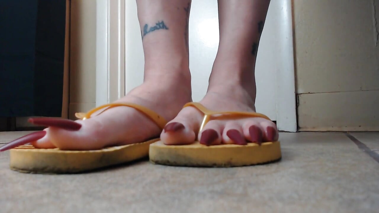 Toenails hanging off yellow flip flops