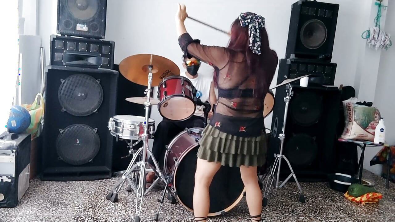 親友の女性が、男性の友人がドラムを演奏している間にセクシーなダンスを披露する。
