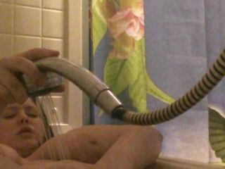 Una bella donna dai seni grandi usa la doccia sul suo clitoride