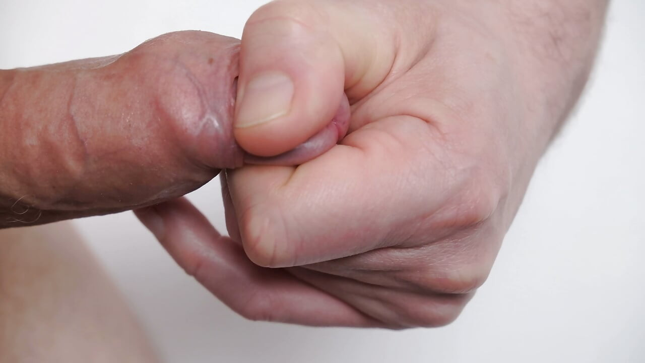 Sangat dekat dengan kulit khatan dan kepala penis seorang pria yang sedang bermain-main dengan kelenjar penis ereksi yang belum disunat