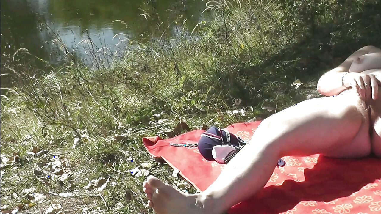 Sexy mature milf sunbathes naked on shore river fingering masturbating hairy pussy and orgasm. Outdoor Outside Naked public Solo