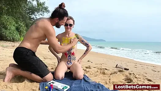A horny couple playing strip tic tac toe on the beach