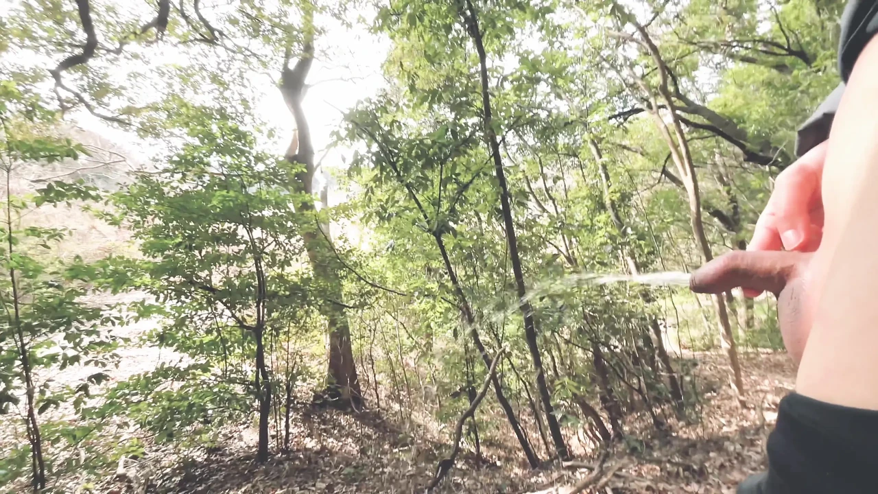 A boy with a small foreskin pees a huge stream outdoors