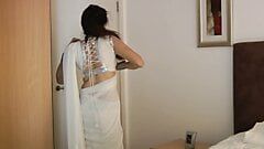 Schönes indisches Schätzchen Jasmin im weißen Sari zieht sich aus