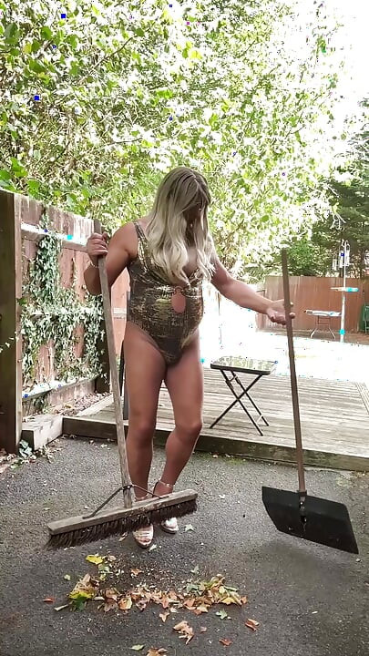 Seksi transvestit kellycd2022 u zlatnom kupaćem kostimu i štiklama čisti lišće