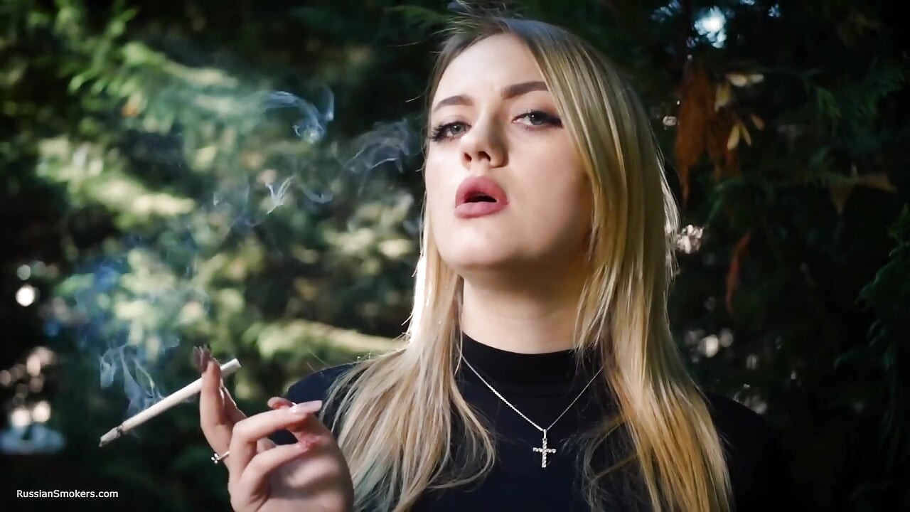 Hot Blonde Babe som røyker en svart sigarett i naturen