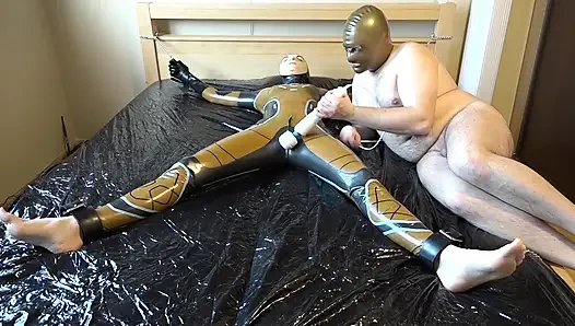 Lateks Danielle yatağa bağlı ve masaj vibratörüyle mastürbasyon yapıyor