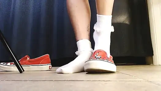 Cewek dengan kaus kaki putih dengan kaus kaki vans flame sneakers lagi asik main sepatu