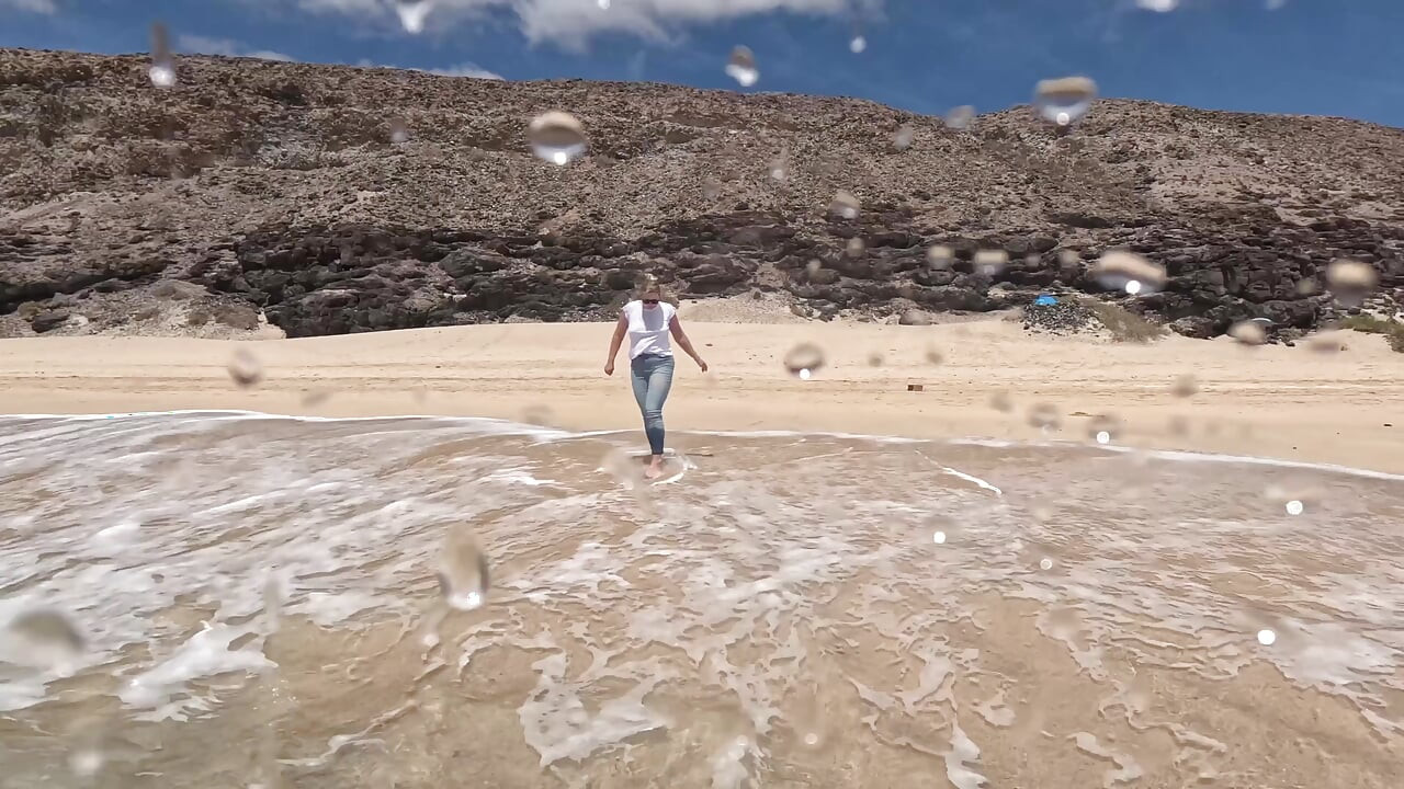 Fată umezind blugii în ocean și înotând în tricou alb umed