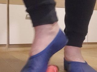 Blaues gymnastisches Pantoffel aus Leder spielt mit einem Dildo