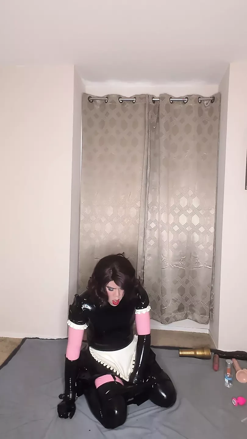 Catsuit lateks dan pembantu rumah banci berpakaian cuba mengongkek kedua-dua lubangnya dengan dildo