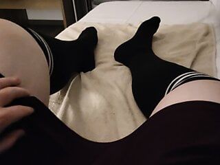 Femboy en falda y calcetines altos se masturba en una habitación de hotel