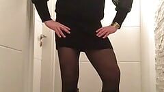 Nicki-Crossdress em um mini-vestido preto sexy, calças justas e botas