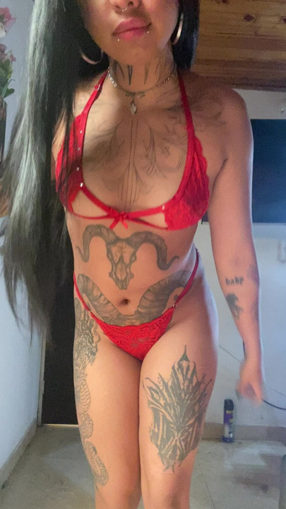 Brunette girl tattooed in red lingerie, showing her body on screen