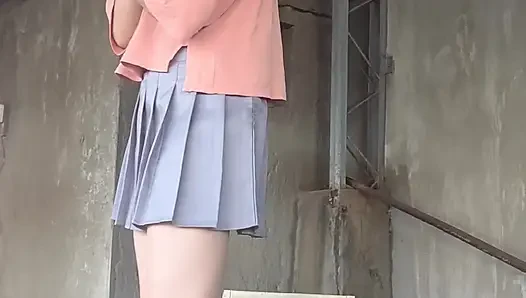 Beyaz iç çamaşırıyla eşleşen pleated bir etek ve terasa anal tıkaç takıyor