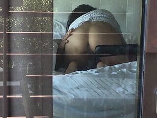 Filmare una coppia bollente mentre guarda attraverso la finestra dell'hotel