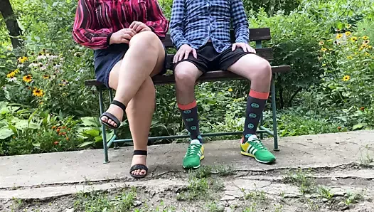 Luxurious stepmother helps her stepson to pee while sitting in the park on a bench