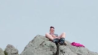 Zoey masturbándose en público en lo alto de una roca en el puerto