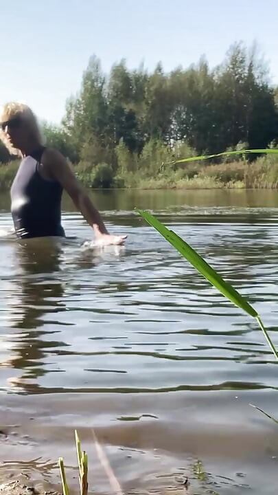 Trans djevojka pliva u jezeru u plavoj sportskoj haljini. Wetllok trans djevojka mokra.