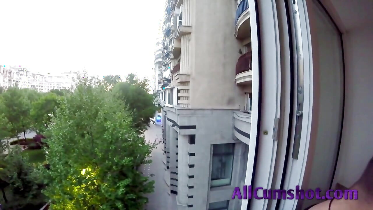 Hij rookt en ontspant zich op het balkon terwijl ze op haar knieën zijn lul zuigt