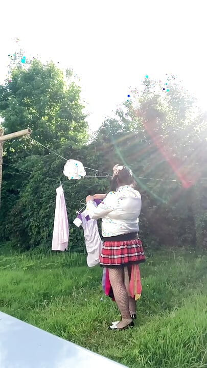In schoolgirl outfit to hang the laundry