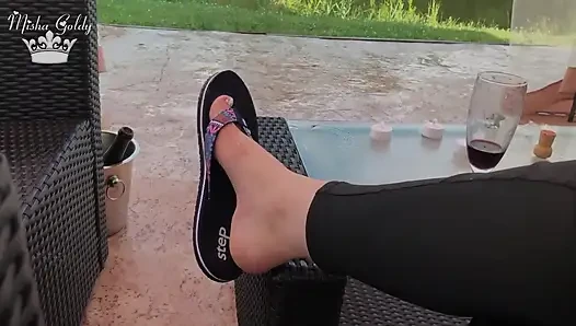 Flip flops dangling outdoor near lake with silver nails & toes wiggling