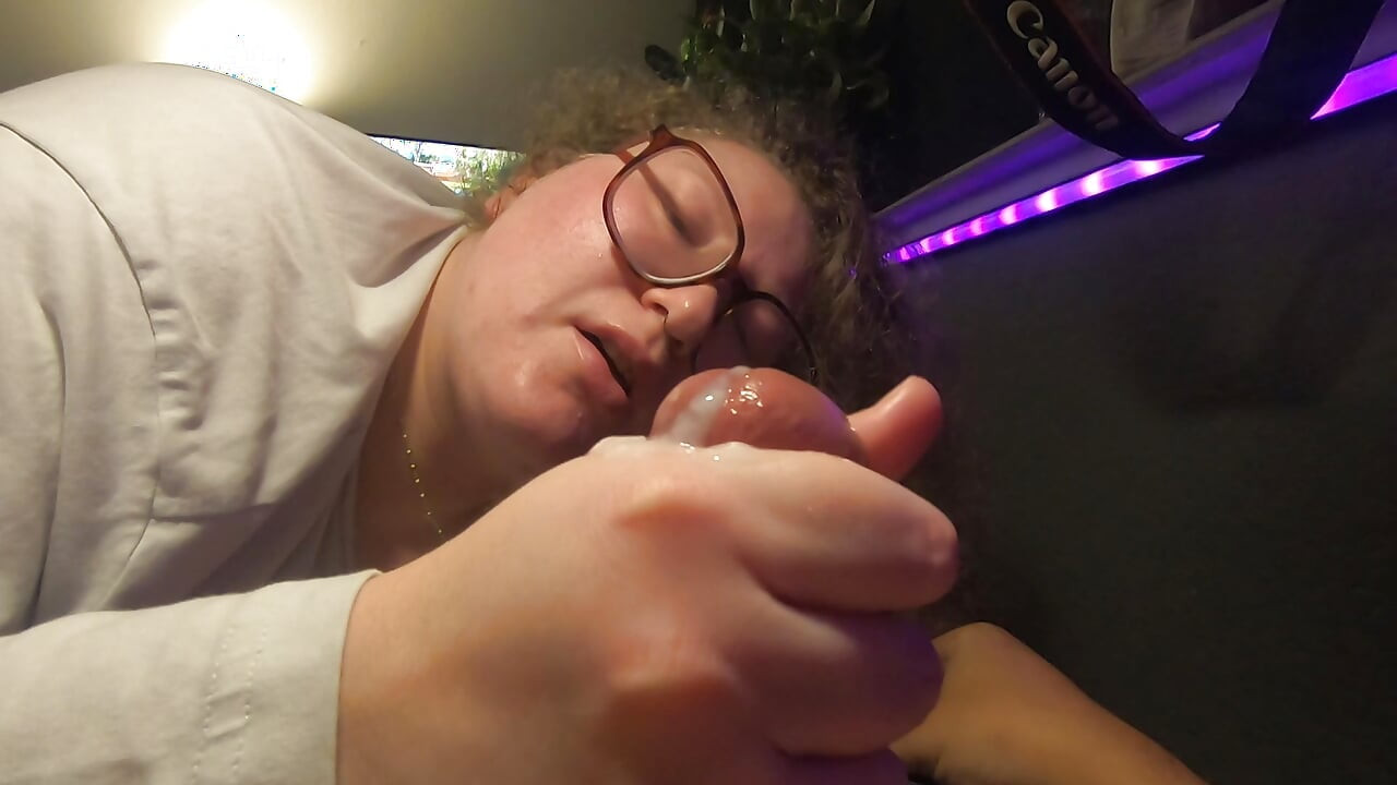 Viaton pullea valkoinen nörttityttö, jolla on silmälasit, imee kullia ja nuolee spermaa