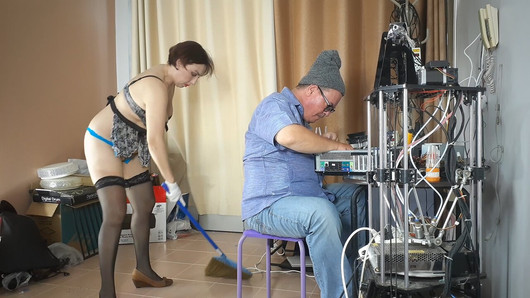 Una criada desnuda está limpiando en la oficina de un ingeniero informático. Un empleado desnudo recoge cables y partes de computadoras en u