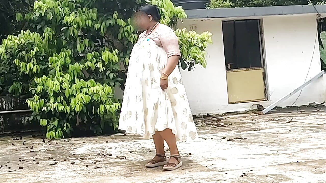 Seorang wanita berbadan montok mengenakan rok putih dan atasan pink melepaskan pakaiannya dan berjalan telanjang di luar ruangan.