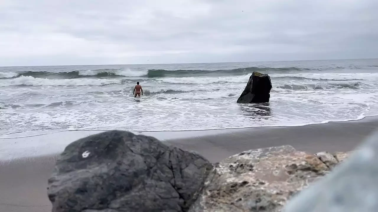 Nua isolada na praia nadando nua no oceano e eu