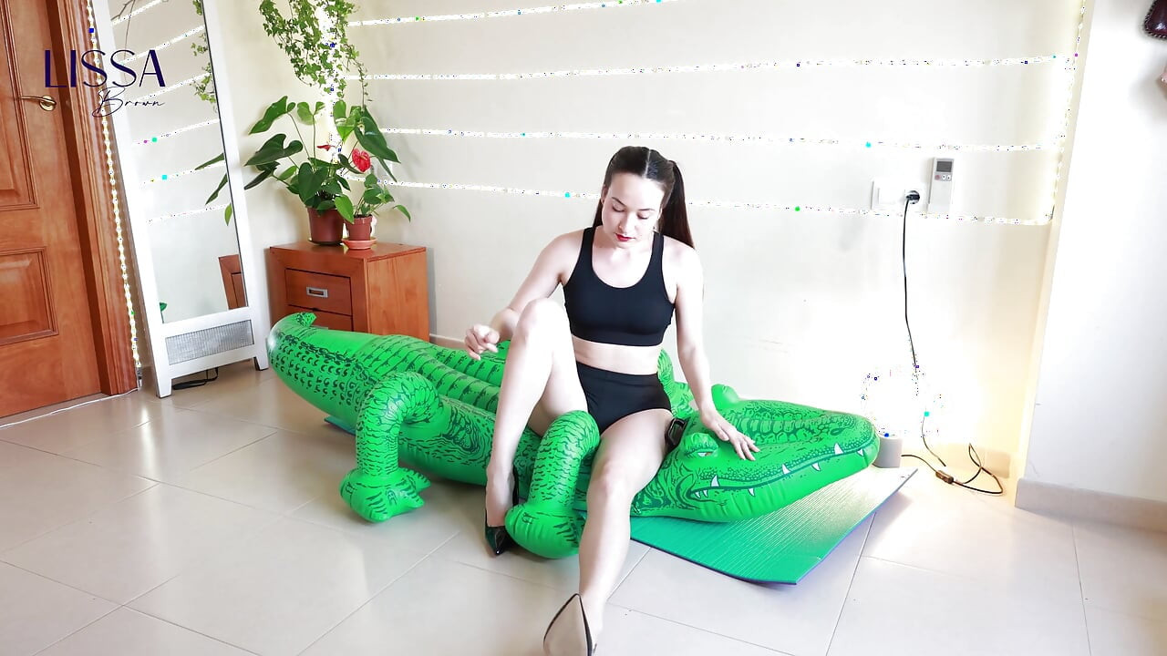 Yoga und Stilettos zerstören das aufblasbare Krokodil.
