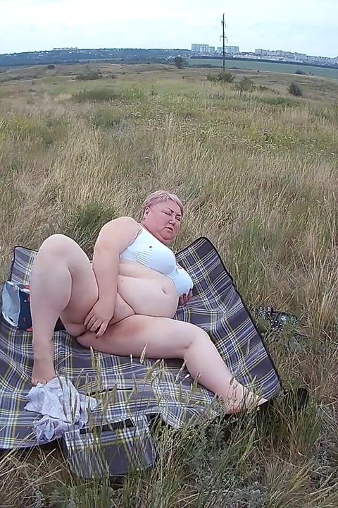 Dikke vrouw masturbeert met een speeltje in het veld