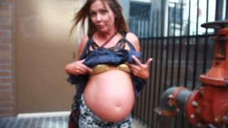 Grávida de rua mostrando a barriga em um top de biquíni