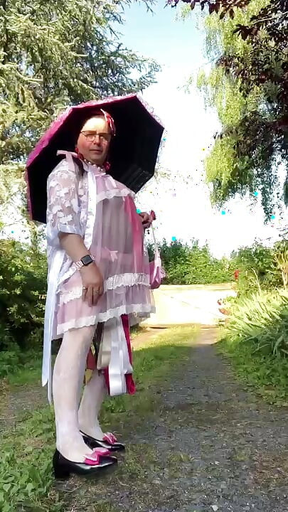 In an outfit with a pink nightgown and a sheer white dressing gown with a parasol