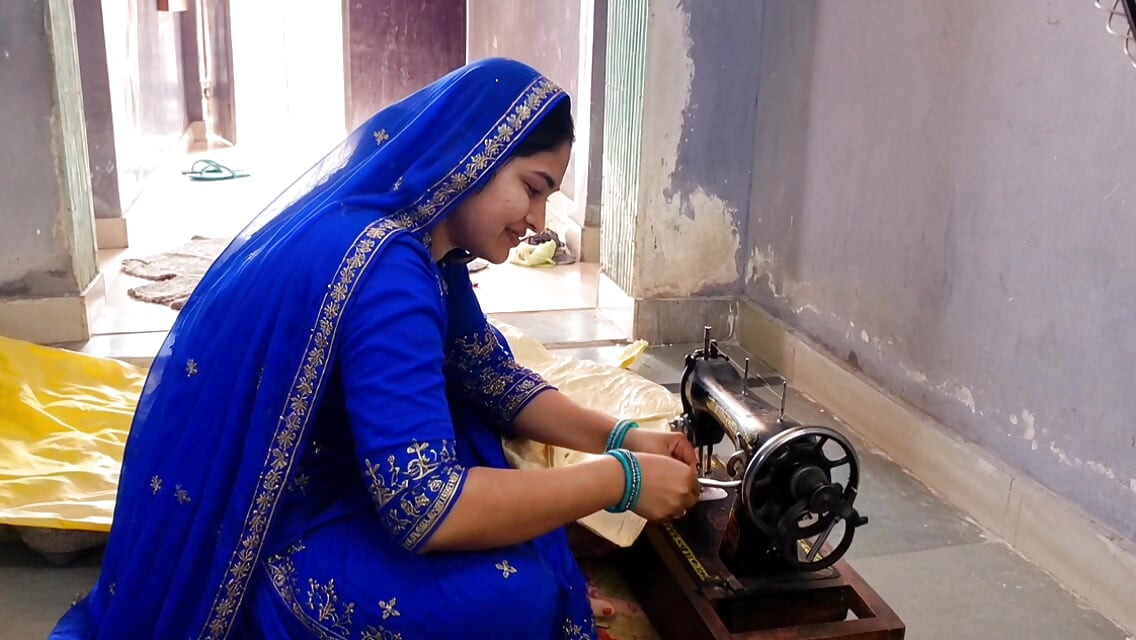 Indische vrouw naaiend op de machine maar ze heeft ook andere gedachten.