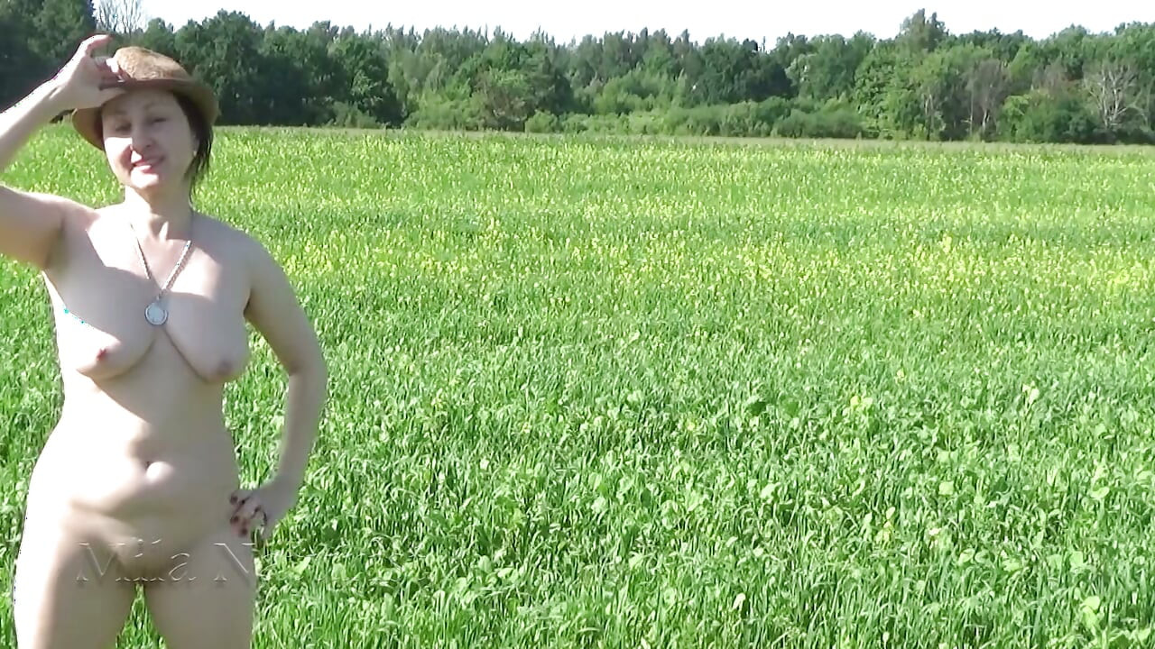 Schöner nackter spaziergang in der wildnis: Fkk posiert in einem grünen frühjahrsfeld