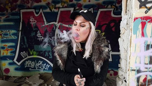 Дама-блондинка курит электрическую сигарету на лестнице