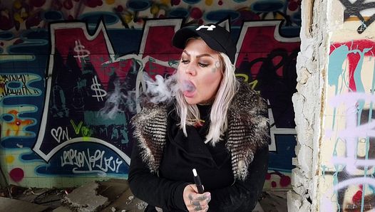 Señora rubia fuma un cigarrillo eléctrico en las escaleras