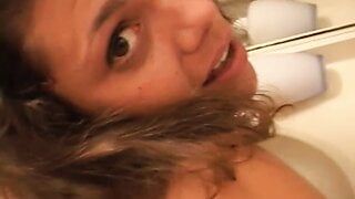 Cute young brunette licks her own tits and gets fucked from behind in bathroom