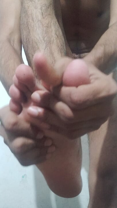 Aplicando una loción corporal en mi cuerpo desnudo y mis pies delante de la cámara