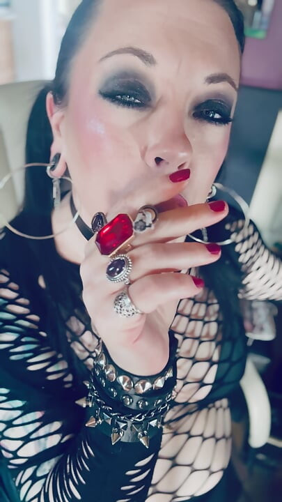 Gotička djevojka Tina Snua s pletenicama puši cigaretu u držaču i pali šibice
