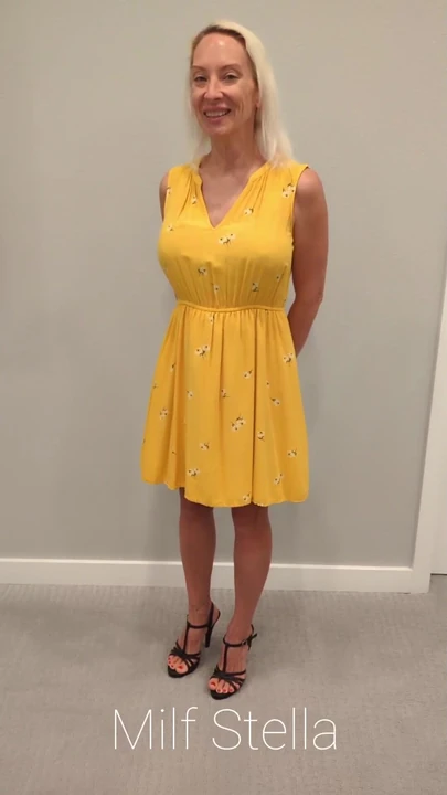 Stella in einem gelben sonnenkleid mit schwarzen absätzen