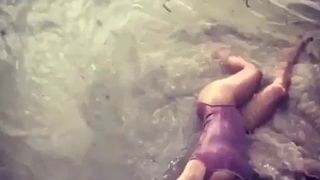 Salma Hayek deitada na água na praia