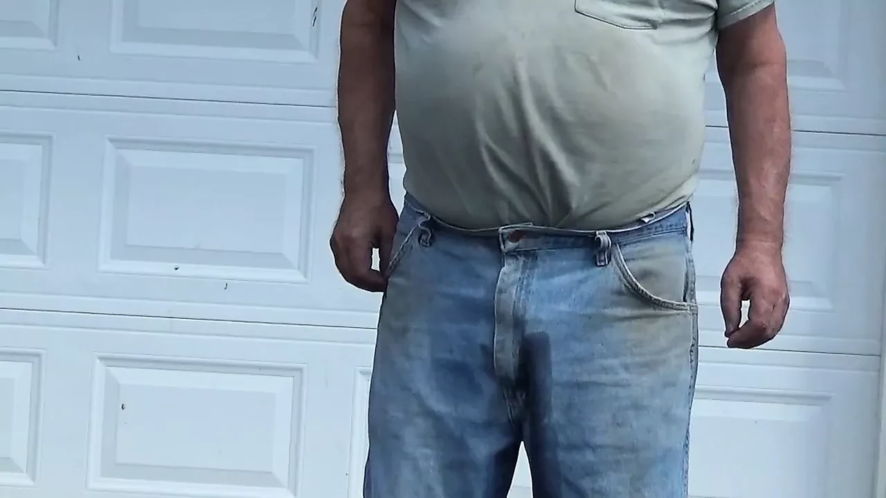 Il vecchio amico piscia in pantaloni davanti al garage
