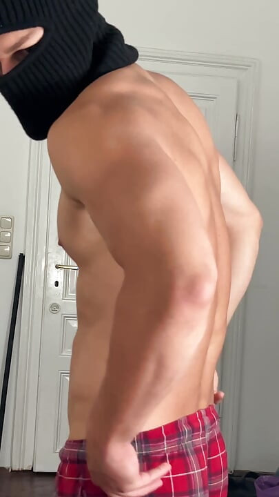 Young bodybuilder flexing his muscles in front of the mirror