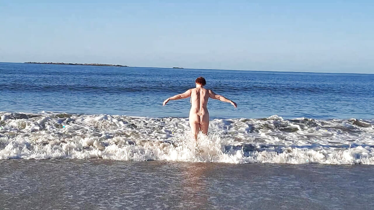 Real nudista brincando nua nas ondas do oceano