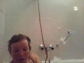 Сексуальная леди одной рукой принимает душ с плохими ногами