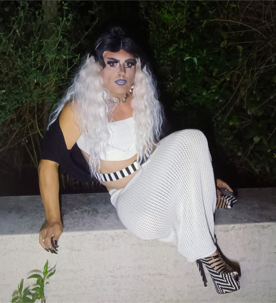 Zreli transvestit u visokim petama puši u parku