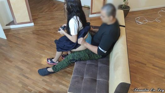無邪気さを利用する老人変態の脚に座ってビデオゲームをする少女