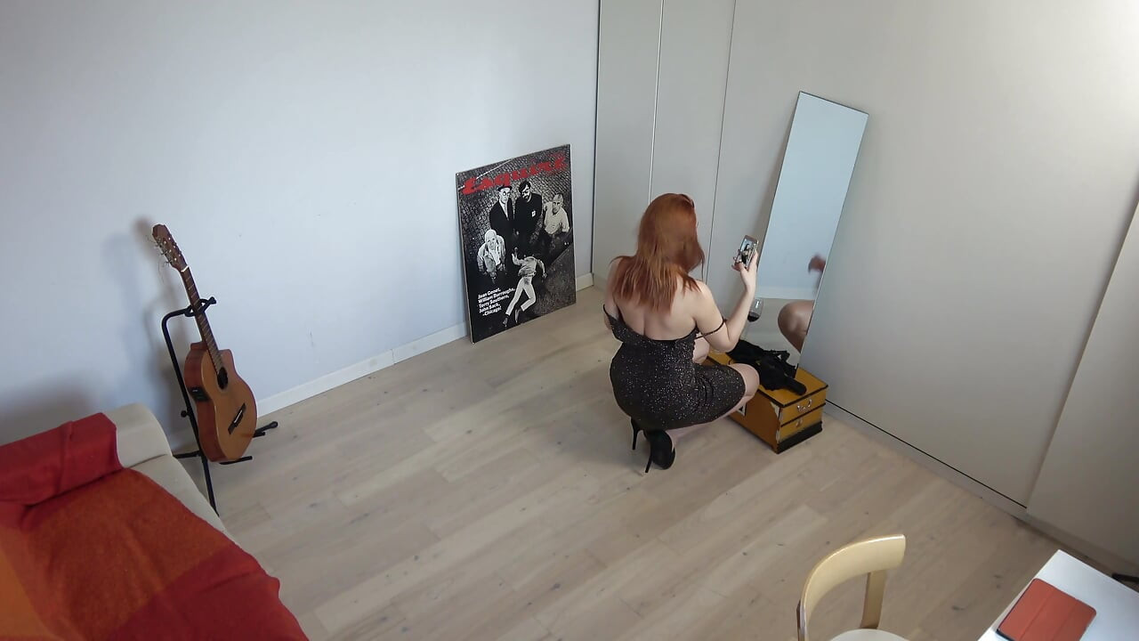 Rudowłosa milf w czarnej spódnicy bierze seksowne selfie przed lustrem